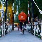 man in red jacket riding bicycle on bridge during daytime