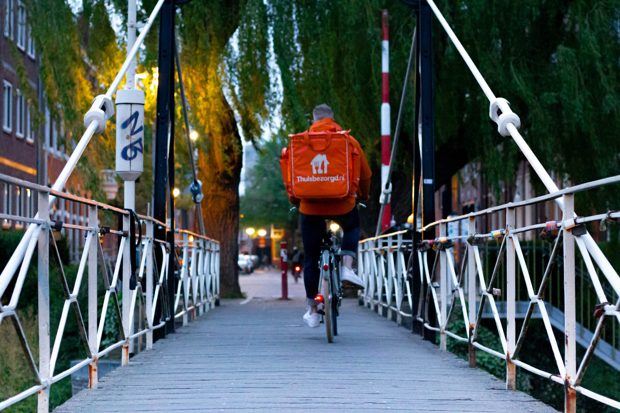 man in red jacket riding bicycle on bridge during daytime